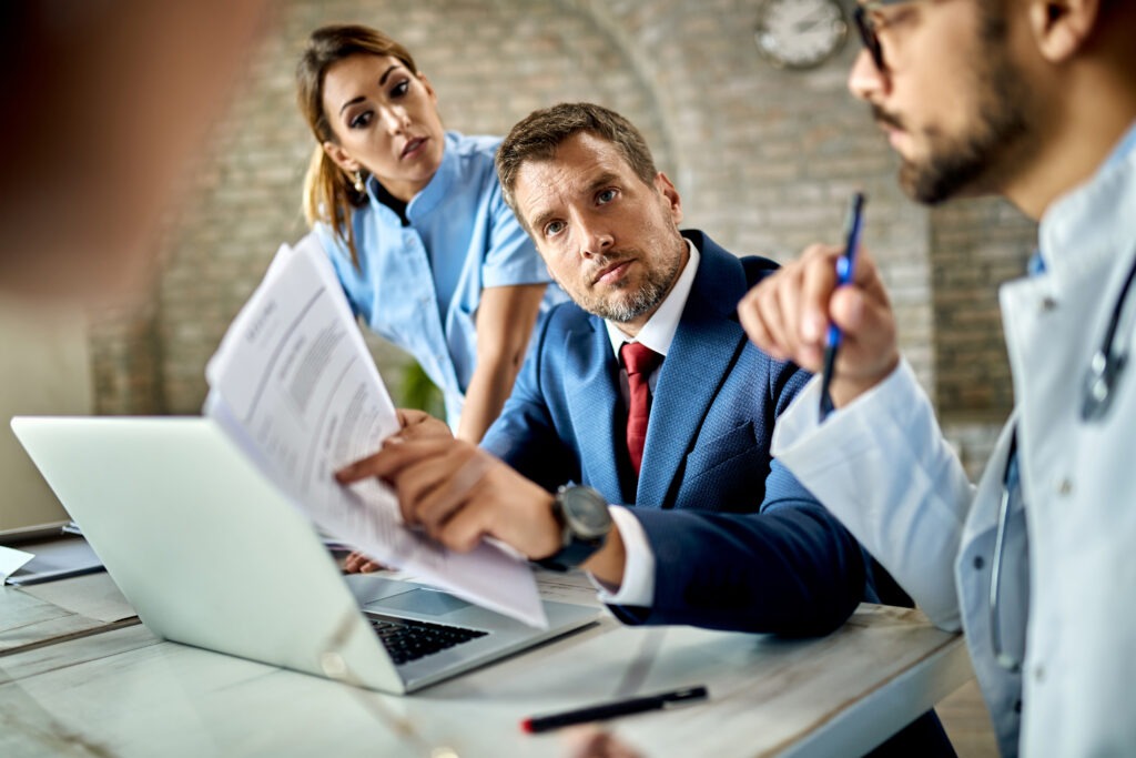 mid adult businessman group doctors analyzing paperwork while having meeting office